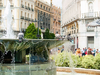 People on fountain against buildings in city