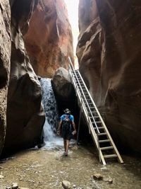 Rear view of man standing in a river front of a waterfall