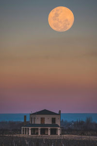 Full frame shot of building against sky during blue hour. full moon. 