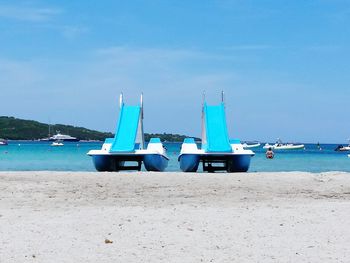 Deck chairs on beach against blue sky