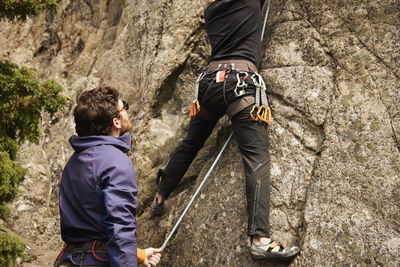 Men rock climbing and belaying