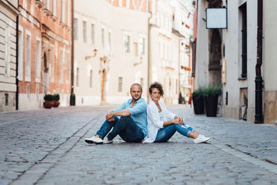 Portrait of friends sitting on street in city