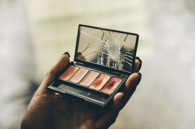 Close-up of hand holding cigarette against blurred background