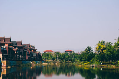 Buildings by lake against clear sky