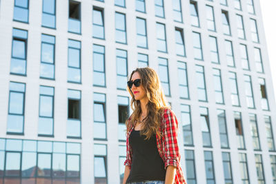 Portrait of young woman standing against building