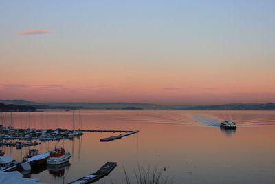 Boats sailing in sea against sky during sunset