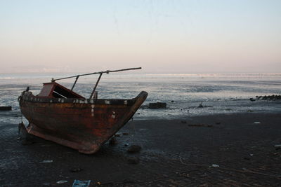 Fishing boat moored on shore against sky