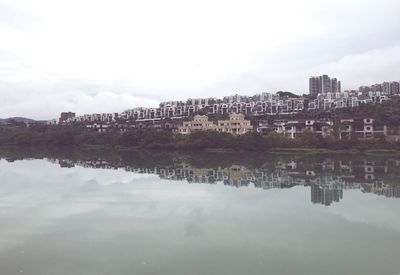 Reflection of cityscape in river against sky