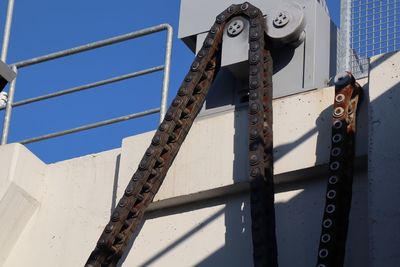 Low angle view of metal chain against sky