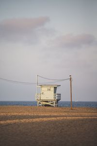 Lifeguard hut on beach against sky during sunset