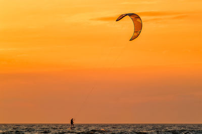 Kiteboarding kitesurfing kiteboarder kitesurfer kites silhouette in the ocean on sunset