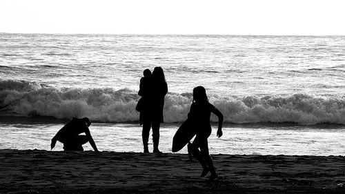 Silhouette people on calm beach