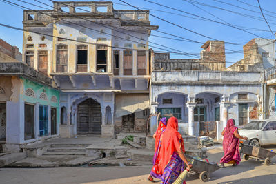 Rear view of people walking on street against buildings