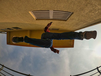 Low angle view of man jumping against sky