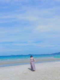Woman standing on beach against sky