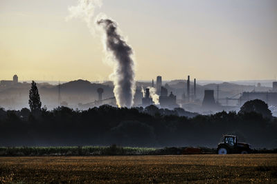Smoke emitting from vehicle on field against sky