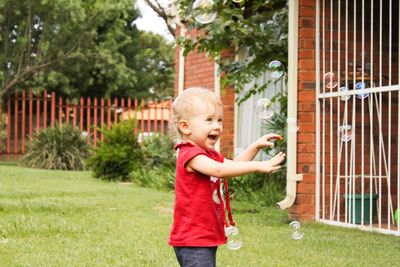 Baby girl playing with bubbles in lawn