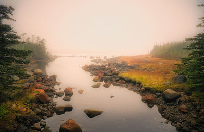 Scenic view of lake against sky during foggy weather