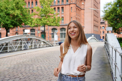 Beautiful cheerful young woman walking and smiling in hamburg, germany