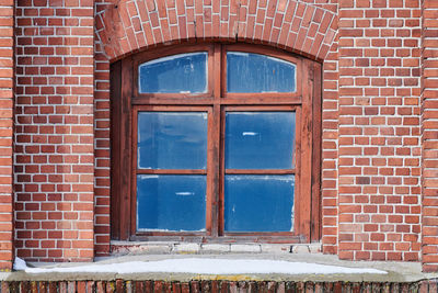 Arched glass window on old red brick wall. vintage window in brown wooden frame on red brick wall