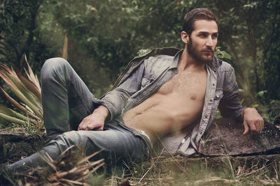 Handsome man lying on field at forest