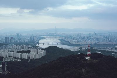 High angle view of city buildings against cloudy sky