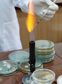 Midsection of scientist with flaming torch doing experiment in laboratory