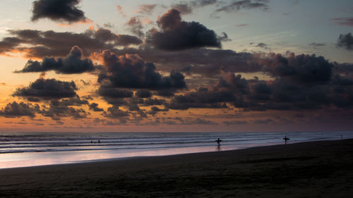 View of calm beach against cloudy sky