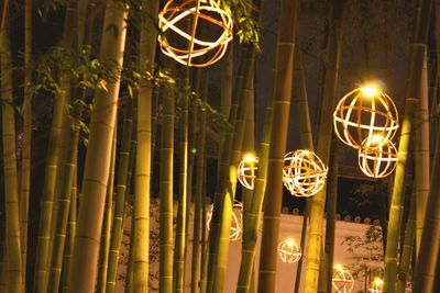 Low angle view of illuminated lighting equipment hanging at night