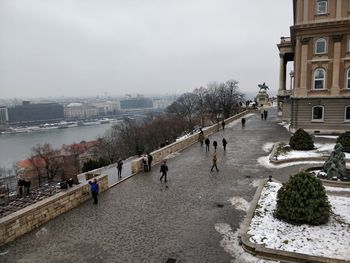 People walking on street in city against sky