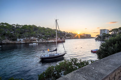 Boat moored on river against sky during sunset