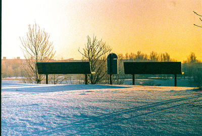 Bare trees on landscape against clear sky during winter
