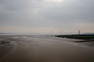 Scenic view of river against cloudy sky