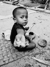 Portrait of cute boy giving food while sitting on floor