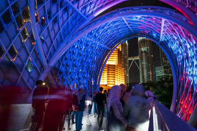 Rear view of people walking in illuminated modern building