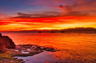 Scenic view of sea against dramatic sky during sunset