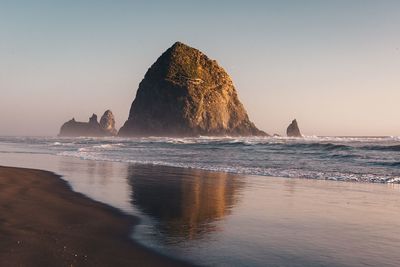 Rock formation on beach against clear sky