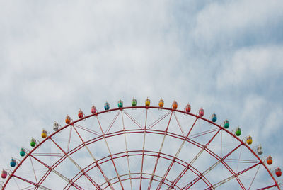 Low angle view of ferris wheel against cloudy sky