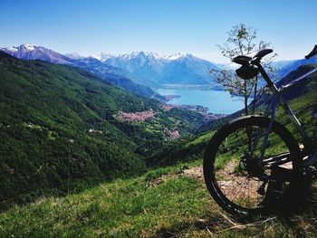 Bicycle parked by mountains against clear blue sky