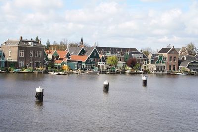Buildings by river against sky