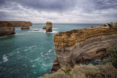 Scenic view of cliff by sea against sky