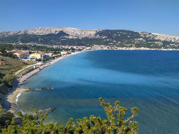 Scenic view of sea and mountains against clear blue sky