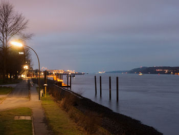 Street light by river against sky