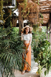 Portrait of young woman standing against plants