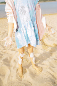 Low section of woman standing on sand at beach