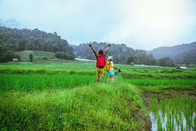 Rear view of people on field against sky