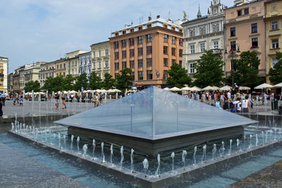 Group of people in fountain against buildings in city