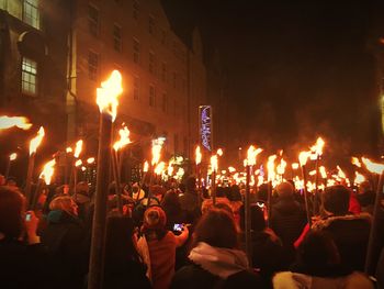 People on illuminated street by buildings in city at night