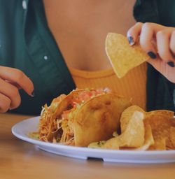 Woman holding a chip with a taco 