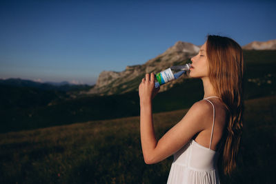 Midsection of woman drinking water on field